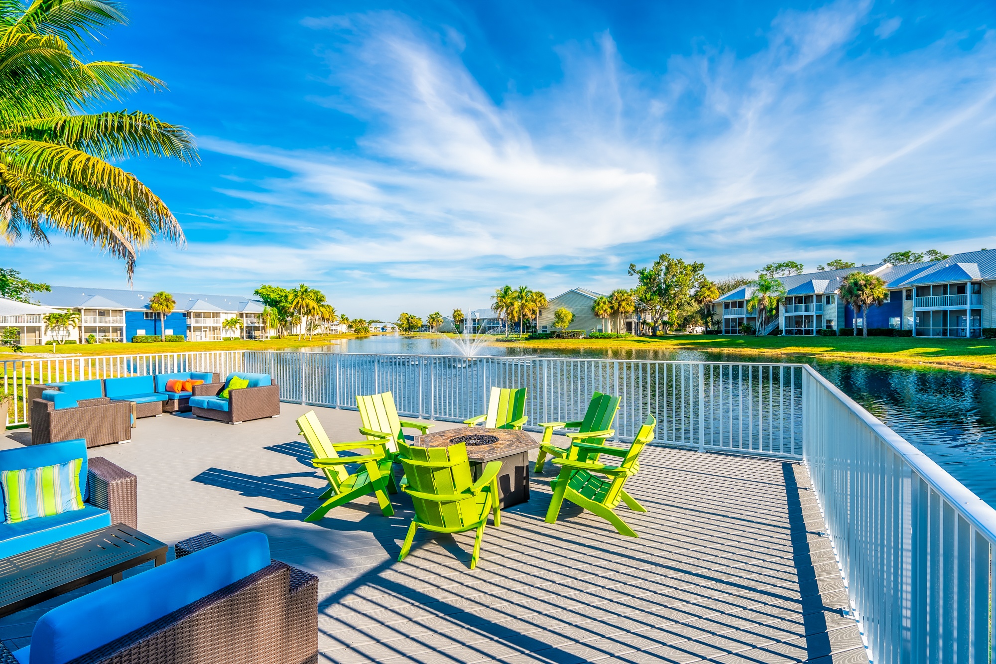 A sunny day at a poolside with a table and chairs.